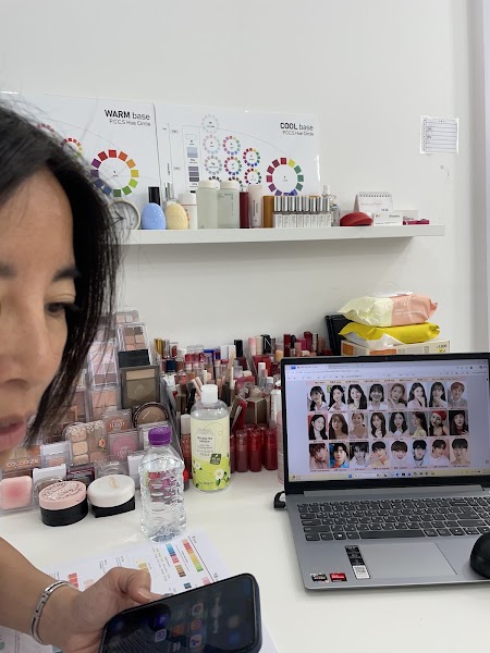 Personal color analysis workspace with cosmetic organizers, color charts, and laptop diagnostic grid