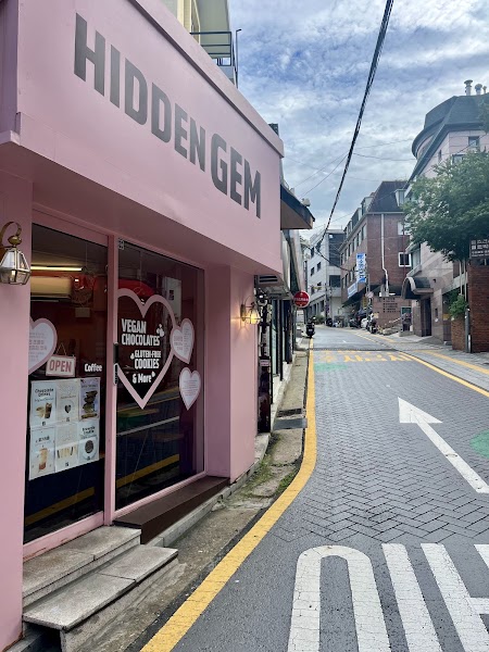 Storefront of Hidden Gem chocolate shop in Seoul with pink walls and large glass display windows