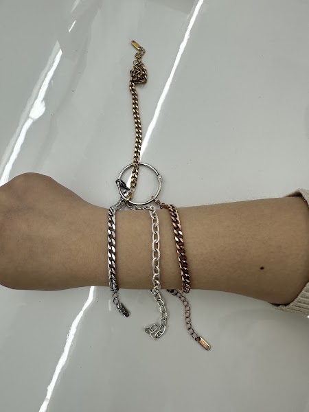 A wrist wearing various metal chains in gold, silver, and rose gold to demonstrate color analysis