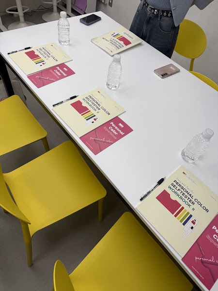 Workbooks and consultation materials arranged on a white table surrounded by bright yellow chairs