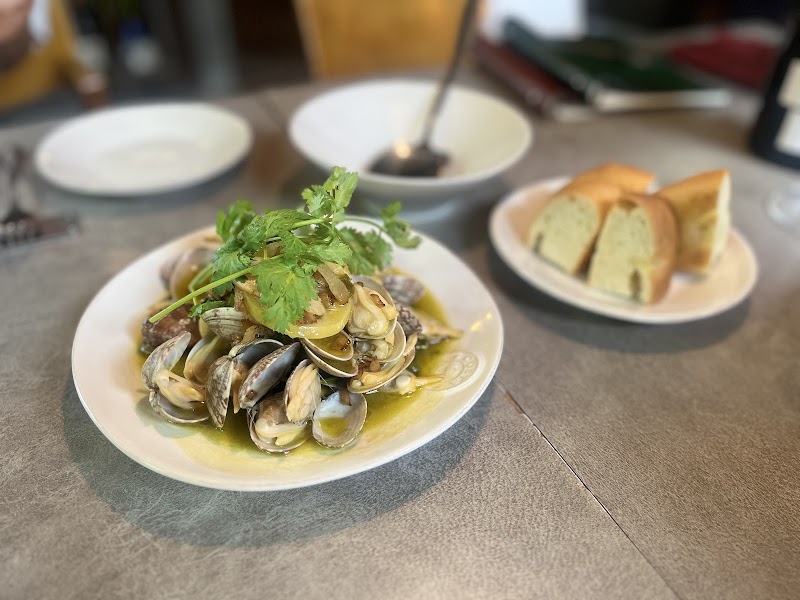 A plate of steamed clams topped with fresh cilantro served with sliced bread