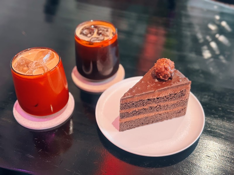 Layered chocolate cake slice served with iced specialty drinks