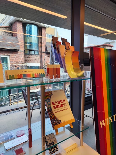 Personal color analysis tools and a rainbow-colored sign displayed on shelves inside a studio overlooking a city street.