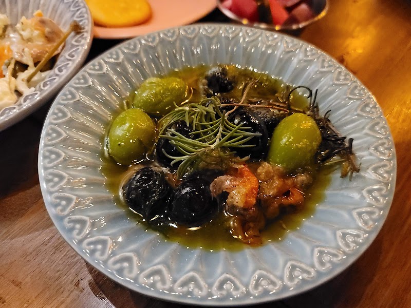 A small plate of marinated green and black olives garnished with fresh rosemary herbs.