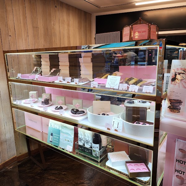 A multi-level glass display case filled with boxes of chocolates and pastries at Hidden Gem