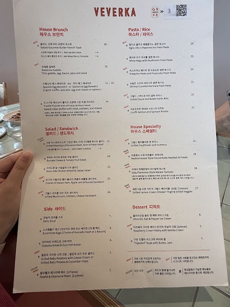 Printed VEVERKA menu held in hand showing brunch sections