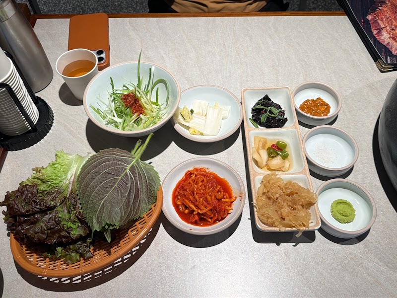 Banchan spread with fresh perilla leaves, scallion salad, white kimchi, and house dipping sauces
