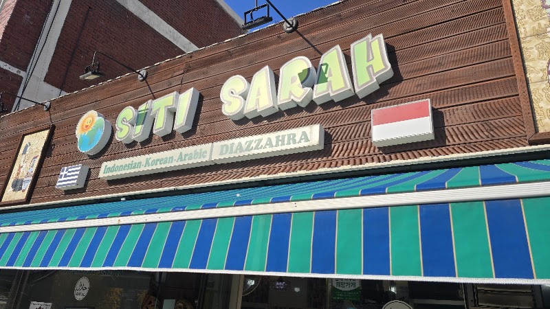 Exterior signage for Siti Sarah Halal restaurant in Seoul featuring a wooden storefront and green-blue striped awning.