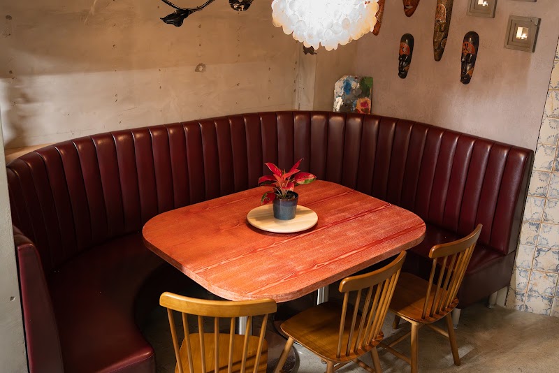 Cozy corner booth with deep oxblood tufted leather seating and wooden dining tables at Hippie Seoul