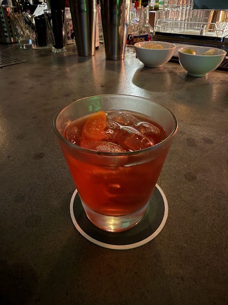 Deep red classic cocktail on a circular coaster at the bar counter