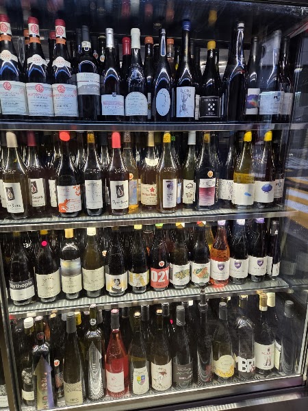 Four-shelf wine refrigerator showcasing diverse natural wine bottles at Gitana