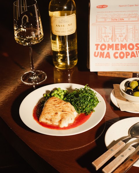 Seared white fish served with green peas, savory sauce, and white wine