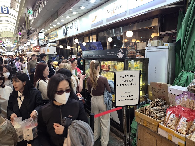 People walking through the bustling indoor Mangwon Market in Seoul, South Korea.