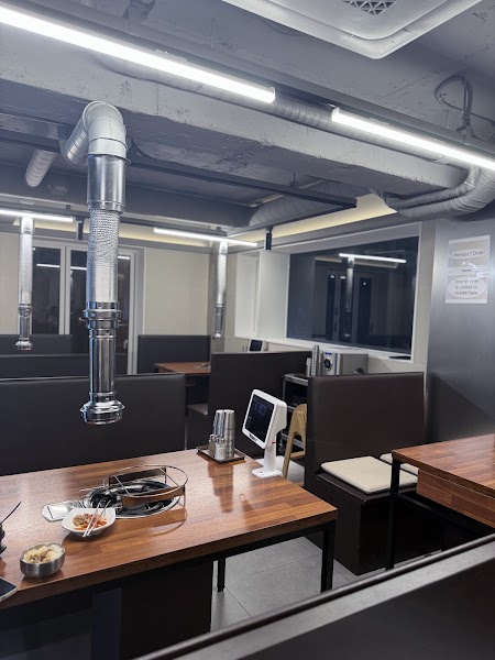 Clean interior dining room with wooden booth tables and overhead smoke exhaust vents