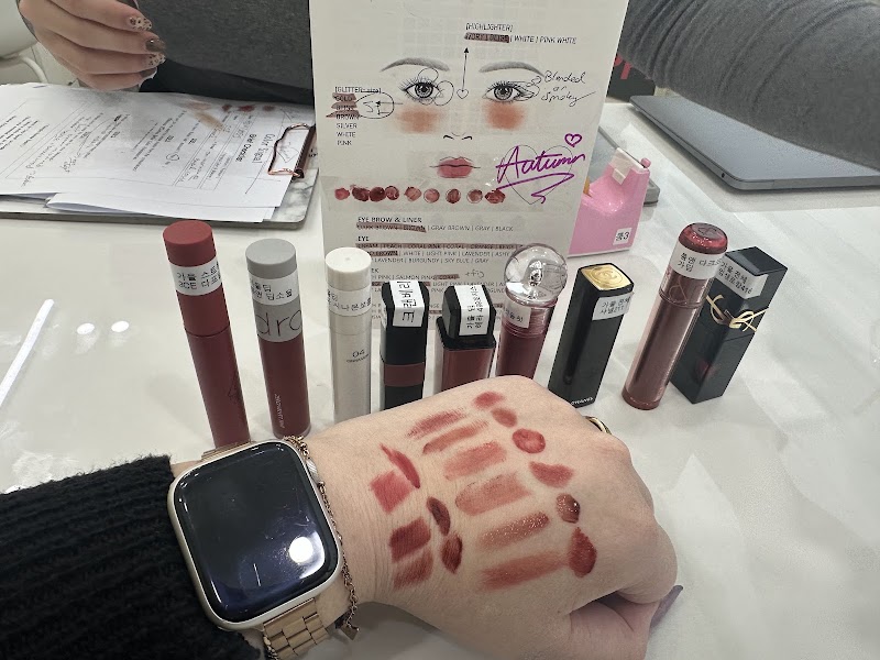Hand showing multiple lipstick swatches with cosmetic products and diagnostic face chart
