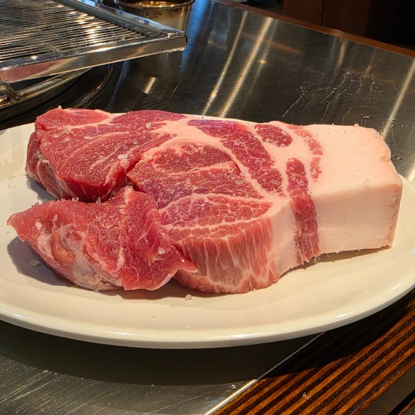 Thick raw cut of pork with visible marbling and coarse salt seasoning