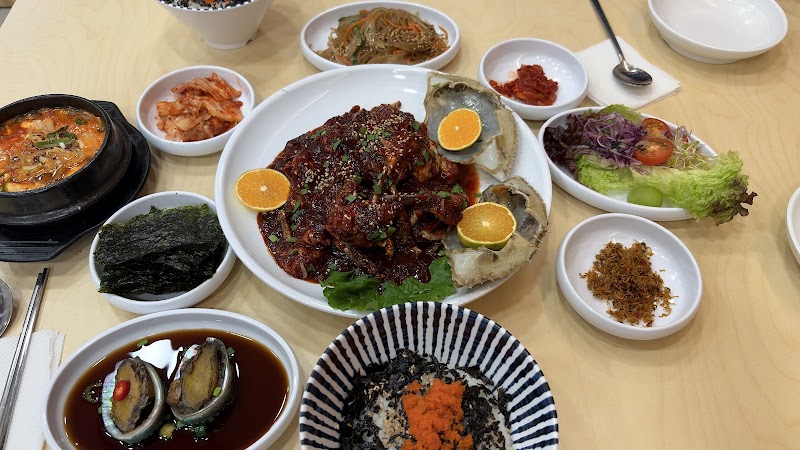 A spread of various Korean side dishes, seasoned banchan, and sauces served on a light wooden table