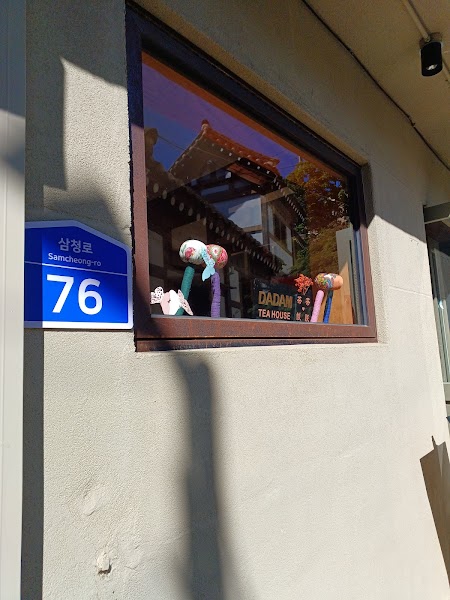 Exterior wall of Dadam Tea House in Seoul with a street address sign and decorative items in the window.