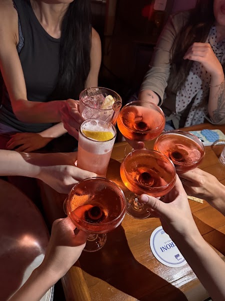 Hands cheering with assorted cocktails over a wooden table at Fabrik Seoul