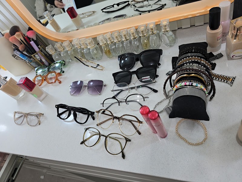 A makeup vanity table with an assortment of eyeglasses, makeup brushes, bottles, and jewelry