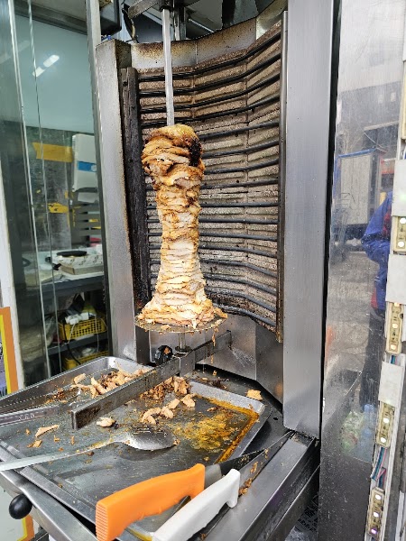 Vertical spit rotating kebab meat in kitchen rotisserie