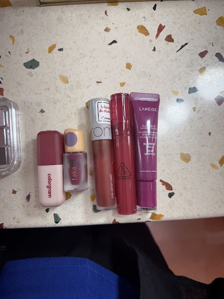 Collection of lip cosmetic products arranged on a speckled countertop for shade testing