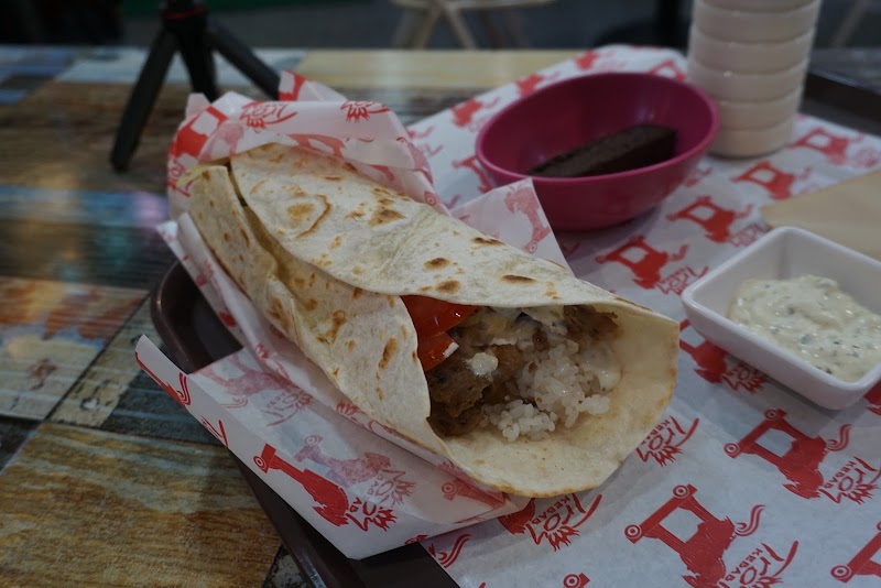 A fresh kebab wrap served with dipping sauce on branded wrapping paper