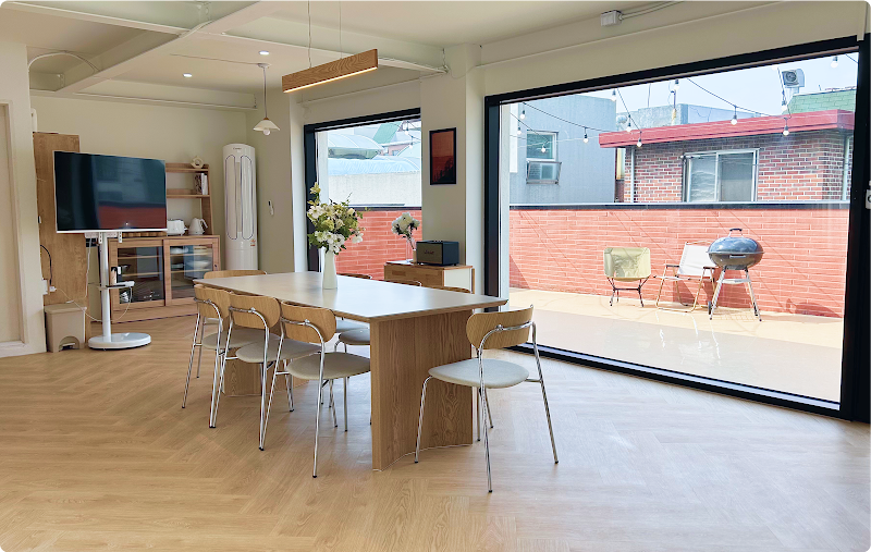 Bright, modern kitchen classroom with a large dining table and access to a terrace with a brick wall and grill.