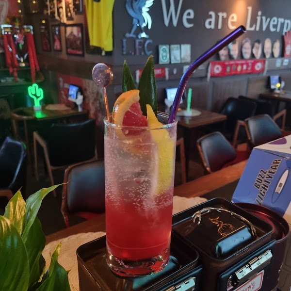 A refreshing red cocktail with citrus garnish and a metal straw served at Liverpool Pub counter
