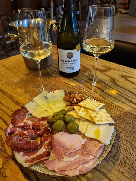 Curated charcuterie board with sliced cured meats, assorted cheeses, green olives, crackers, and almonds