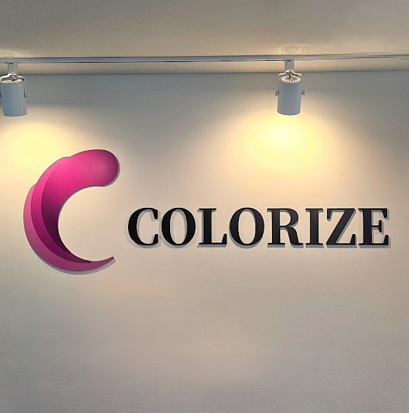 The Colorize brand logo featuring a stylized pink letter C and bold black lettering on a plain light wall