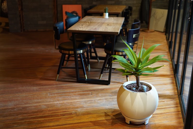 Cozy interior dining corner with wooden table, matte black seating, and spherical potted plant