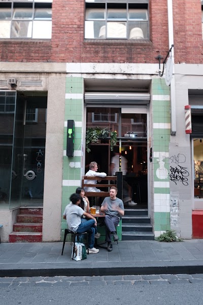 Exterior facade of Bard's Apothecary with green tile framing and street seating