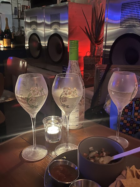 Wine glasses and candle glow in front of large brushed-metal audio speakers