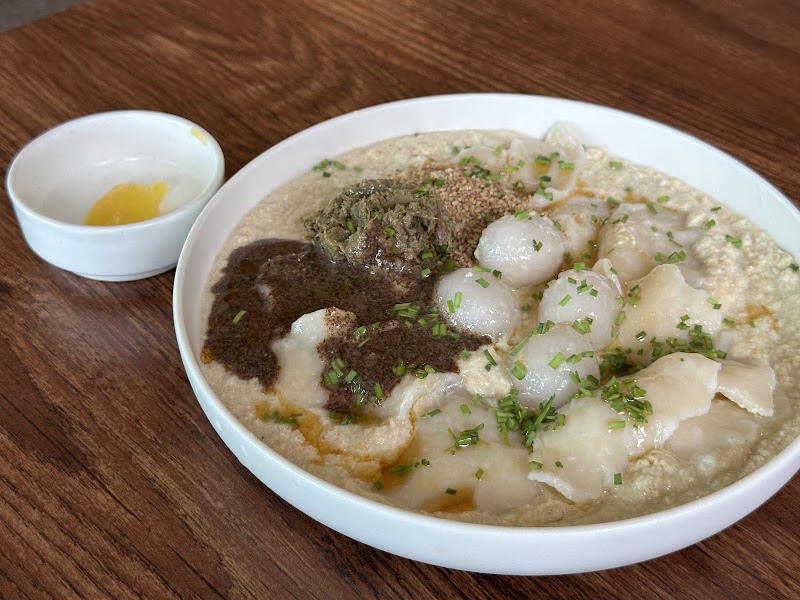 Handmade dumplings served in a ceramic bowl with dark herb paste and chopped chives at de mitt
