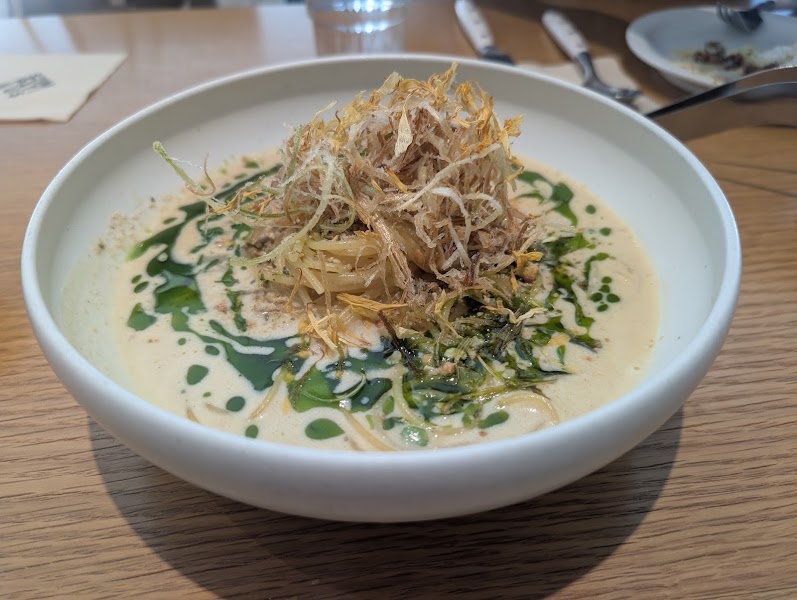 Creamy pasta bowl with vibrant green herb oil and crispy garnish