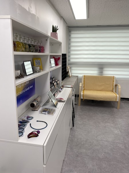 Interior view of a minimalist office or consultation space with white shelving, a yellow chair, and desk accessories.