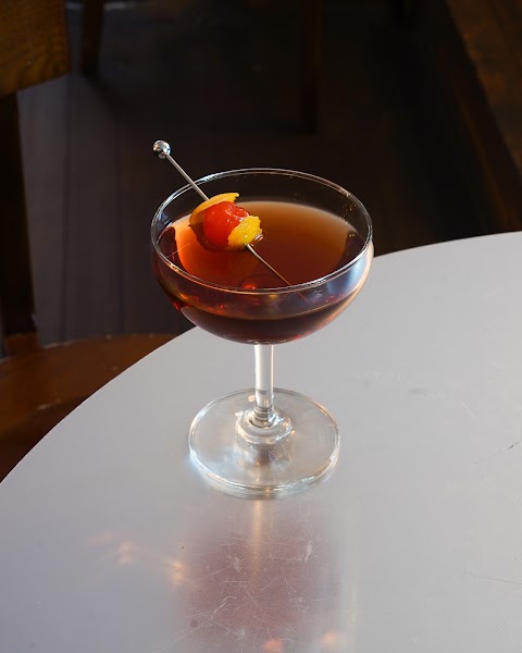 Classic amber cocktail served in a coupe glass with cherry garnish