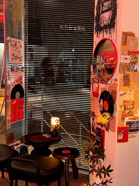 Corner wall with vintage music posters, vinyl records, and table seating