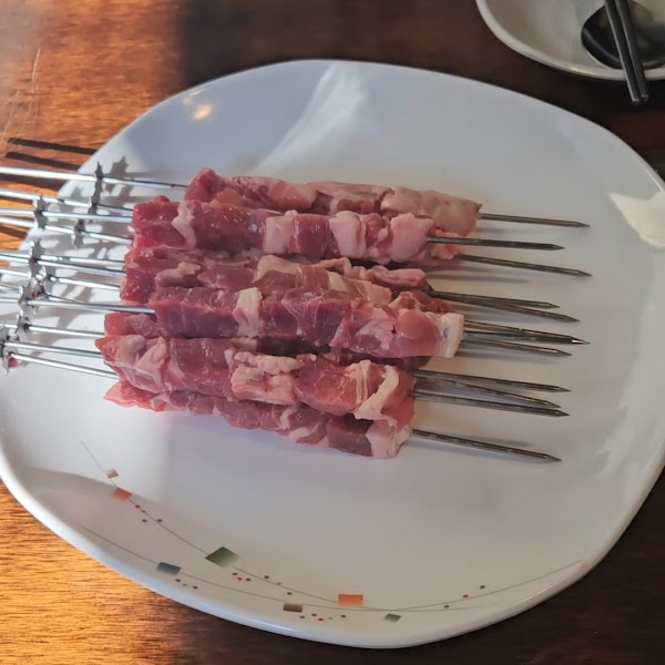 Fresh raw lamb skewers prepared on a white plate ready for the charcoal grill