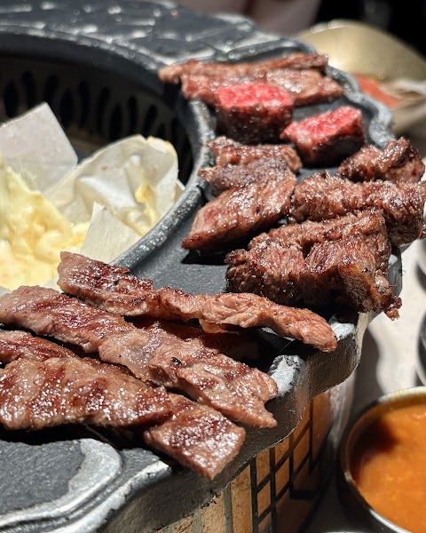 Close-up of grilled meat cooking on a cast iron Korean barbecue grill at Lee Jung Won restaurant in Seoul.