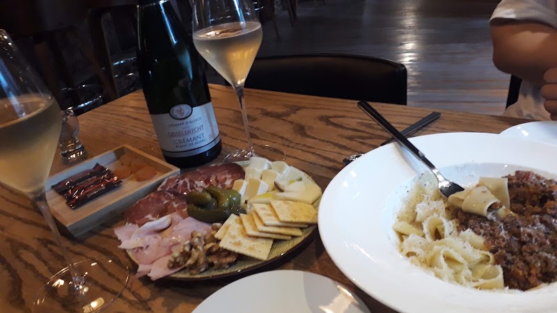 A full dining table setting with Crémant d'Alsace sparkling wine, charcuterie platter, and ragù pasta
