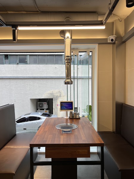 A wooden dining table at Namsan Garden Korean BBQ with a built-in grill and hanging smoke exhaust