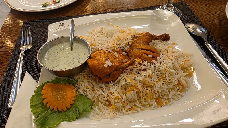 A plate of chicken biryani served with raita and a carrot garnish at Saffron restaurant
