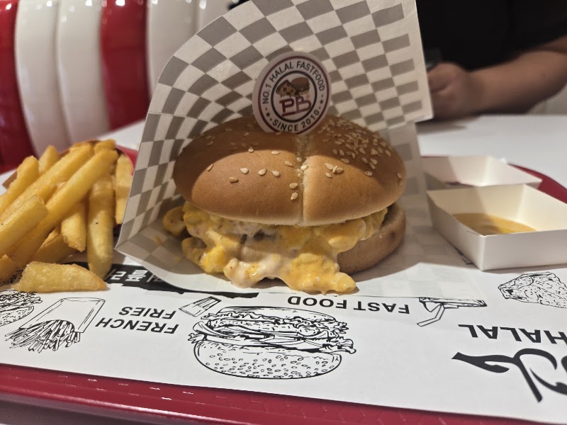 A cheeseburger with melted toppings and fries on a branded fast food tray liner.