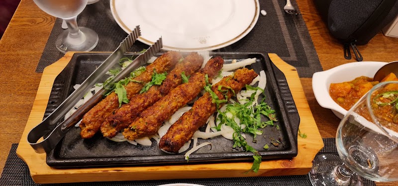 A sizzling platter of four skewered meat kebabs served on a bed of sliced onions with fresh herbs at Saffron restaurant