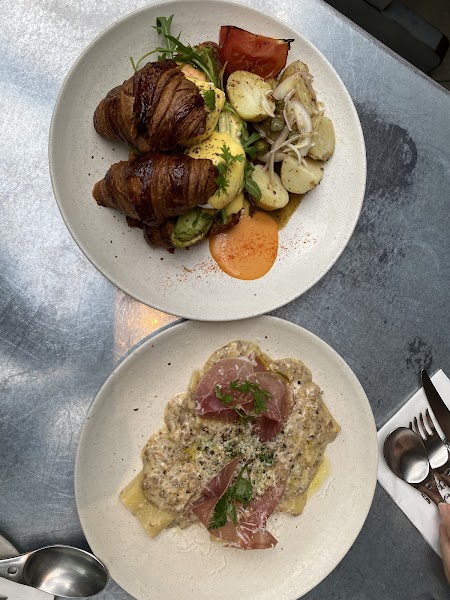 Curated brunch selection featuring sandwiches, roasted potatoes, and pasta on metal table