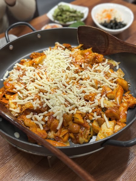 Dakgalbi spicy stir-fried chicken with cabbage and melted mozzarella cheese in a skillet