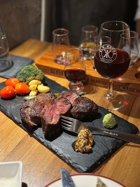 Seared steak served on black slate with roasted tomatoes and a glass of Port wine