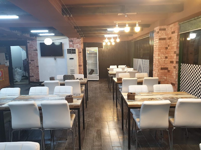 Empty restaurant interior at Bakso Bejo Korea with wooden tables, white chairs, and brick wall accents